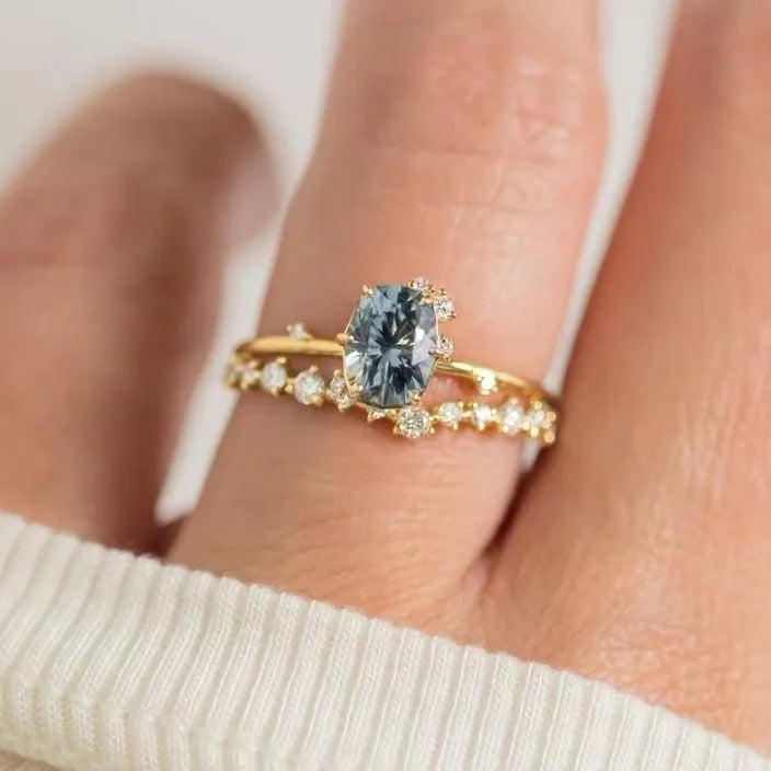 Gold-plated floral women's ring with a central green zircon stone on a model's hand.
