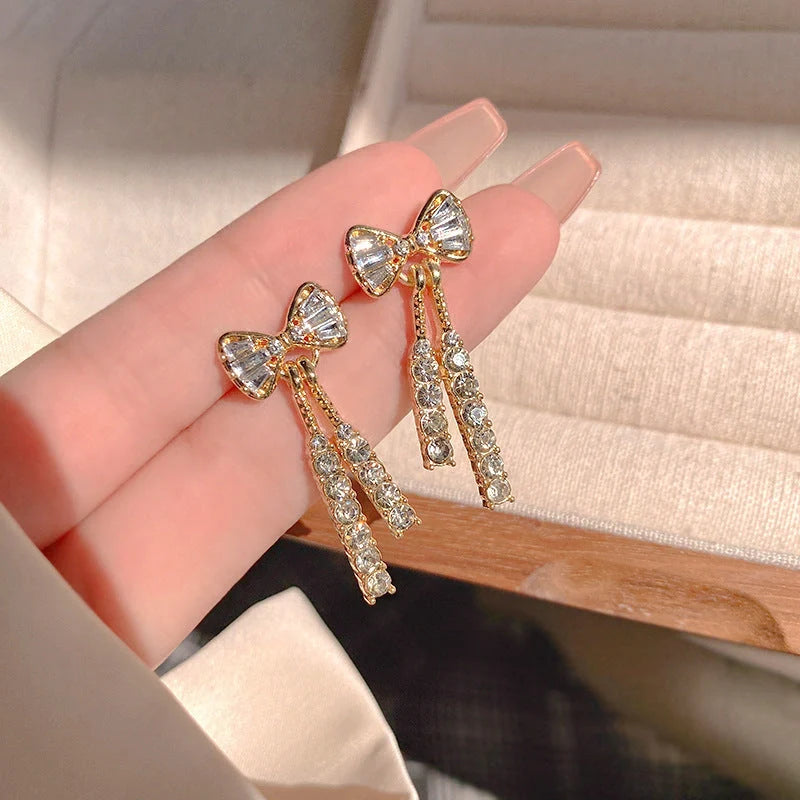 Gold bow-shaped earrings with crystal embellishments, lightweight and elegant
