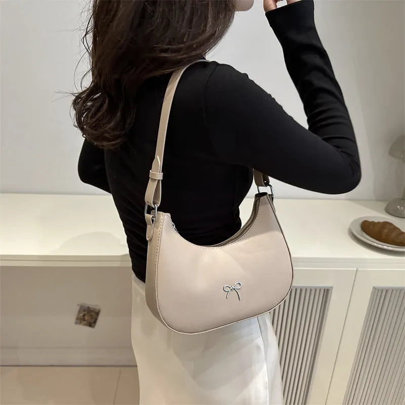 Women's silver dumpling-shaped PU crossbody bag showing front sandwich pocket and single shoulder strap.