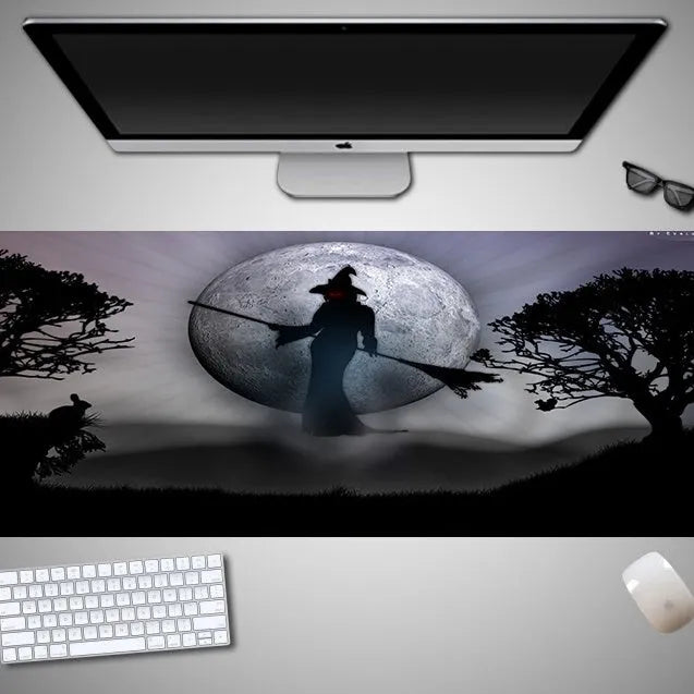 Oversized black mouse pad with Halloween-themed graphic, shown on a wooden desk with keyboard and gaming mouse.