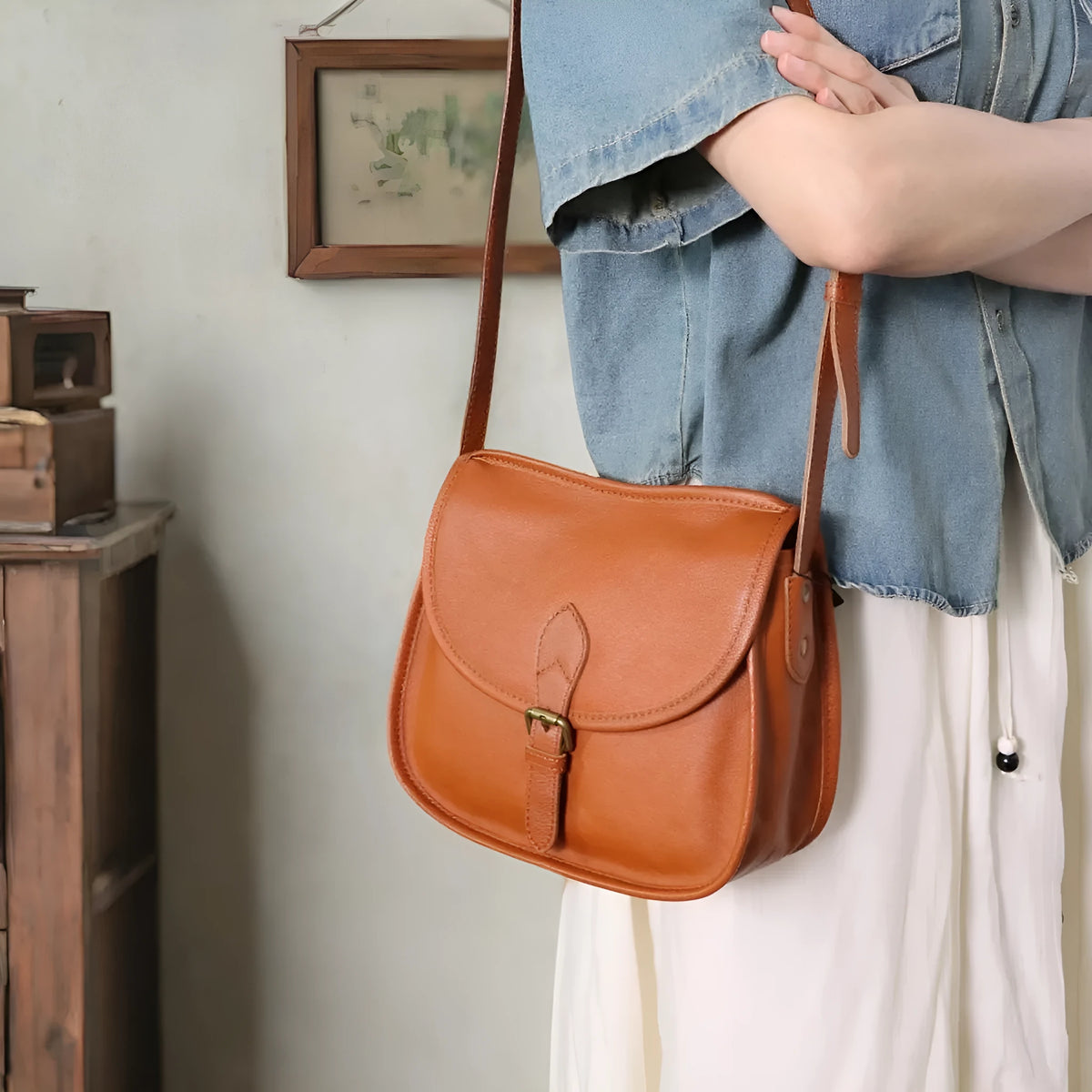 Genuine leather messenger bag in brown colour showing flap closure and textured cowhide material