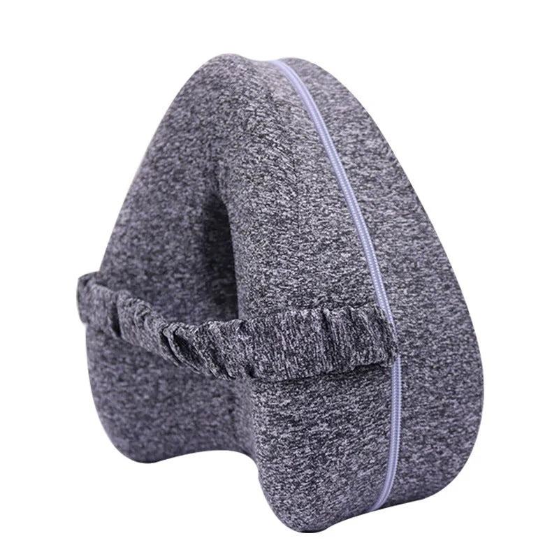 Dark blue jacquard heart-shaped memory foam leg pillow for adults on a bed.