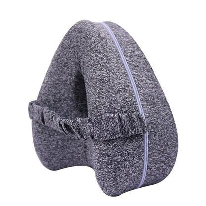 Dark blue jacquard heart-shaped memory foam leg pillow for adults on a bed.