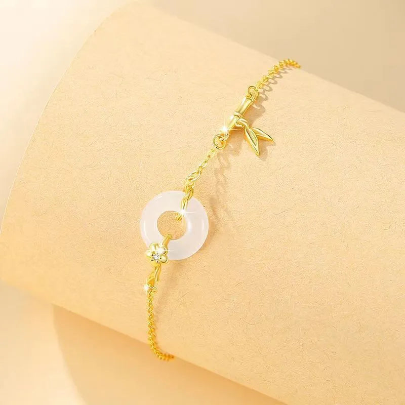 Gold-colour women's bracelet with peace symbol buckle and white chalcedony stone on silver band.