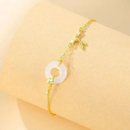 Gold-colour women's bracelet with peace symbol buckle and white chalcedony stone on silver band.