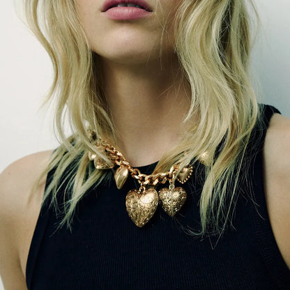Gold carved heart pendant necklace on adjustable chain, showing exaggerated shape and textured details