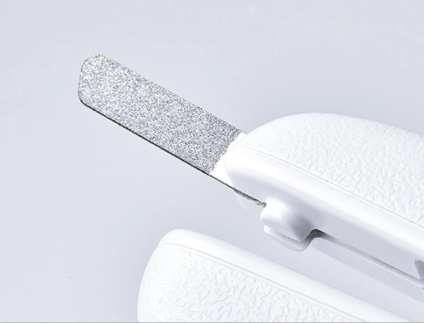 White pet nail clippers with LED light, anti-splash guard, and built-in nail file on a flat surface.
