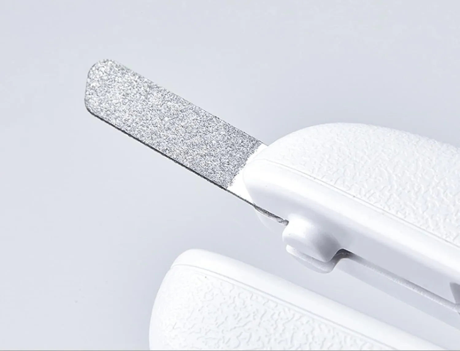 White pet nail clippers with LED light, anti-splash guard, and built-in nail file on a flat surface.