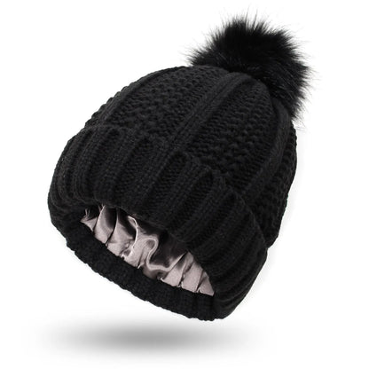 Wool knit beanie hat for women with faux fur pom pom and satin lining, shown in a wine red colour.