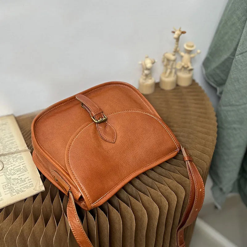 Genuine leather messenger bag in brown colour showing flap closure and textured cowhide material