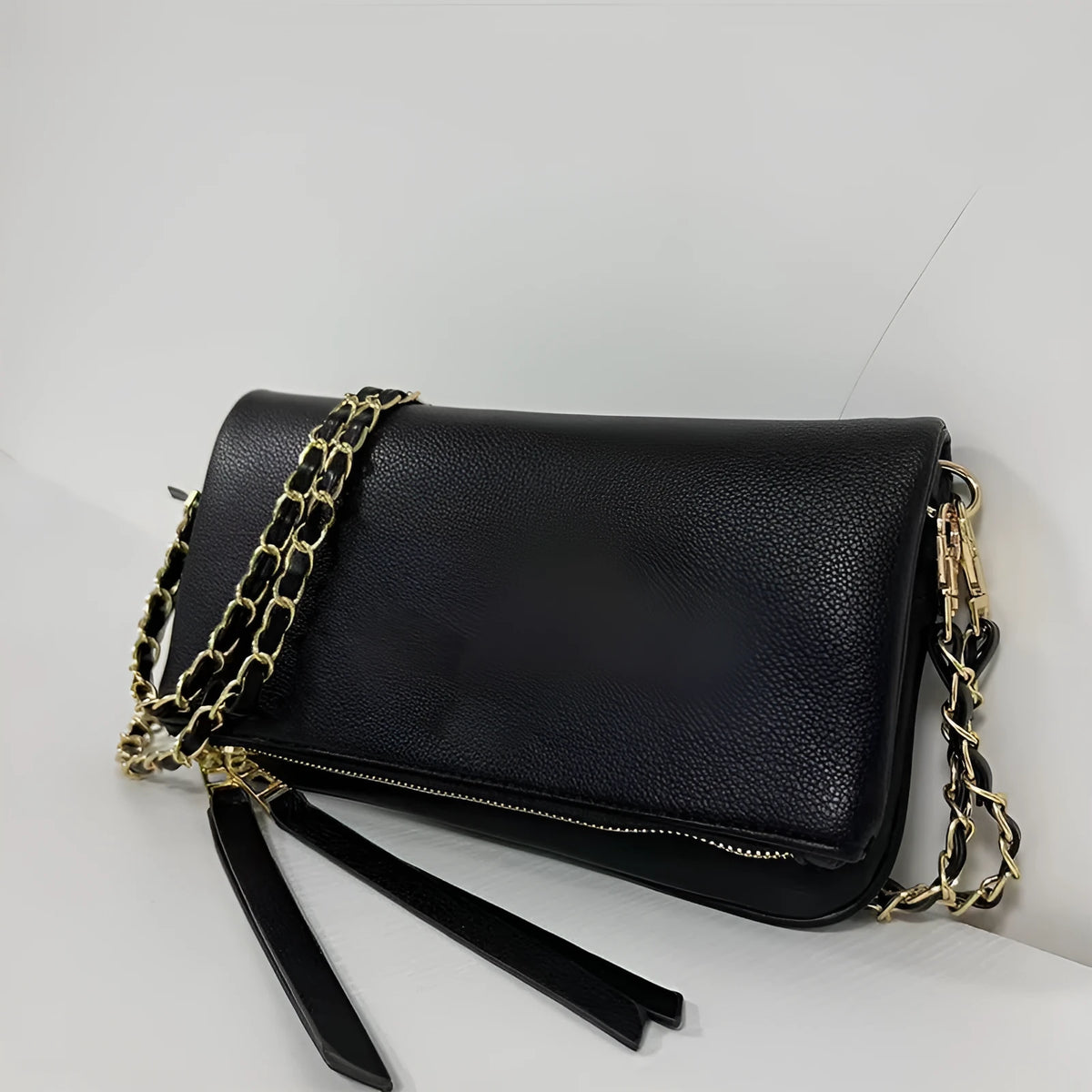 Soft black PU leather women's clutch bag with a gold chain strap, shown held and worn cross-body.