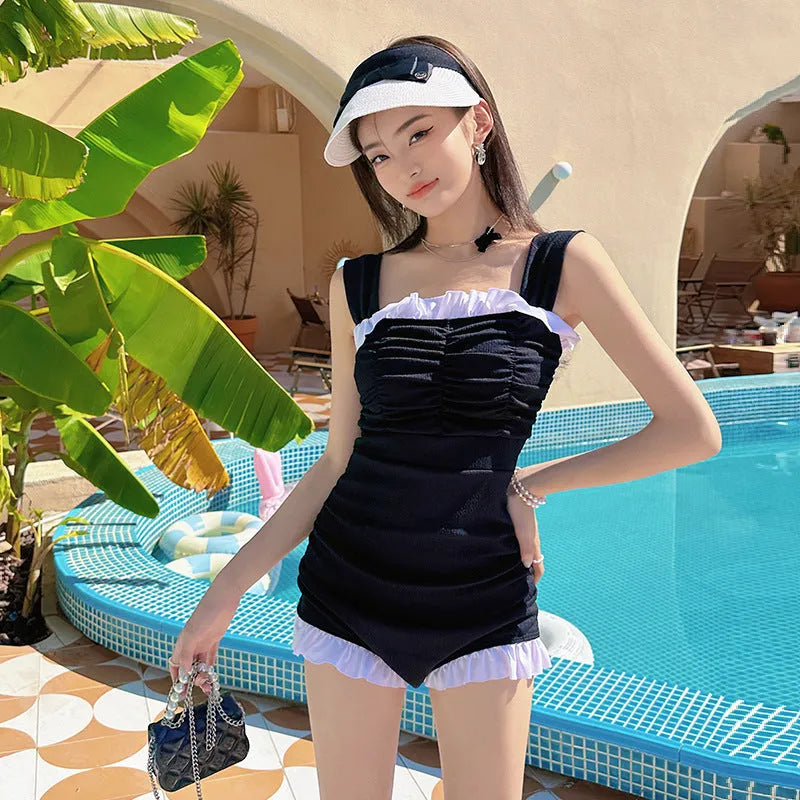 Women's solid colour one-piece swimsuit with suspender straps in pink, green, or black.