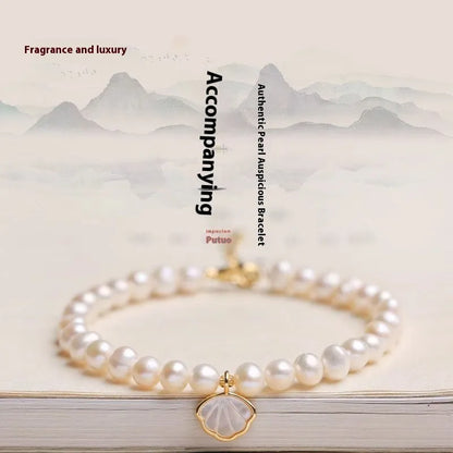 Women's freshwater pearl bracelet with fan-shell centrepiece on a 16cm elastic string or extension chain.