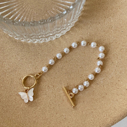Gold charm bracelet with pearl and butterfly design for women