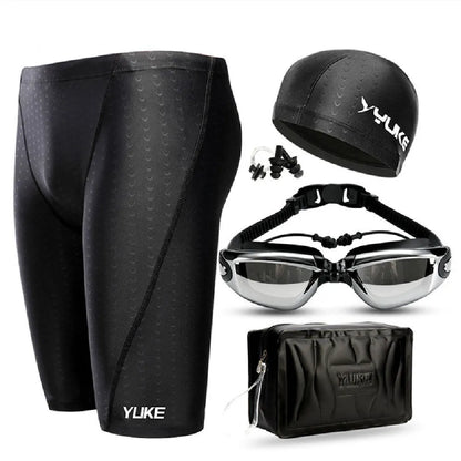 Men's black swimming trunks, goggles, and cap set laid out with ear plugs and carry bag