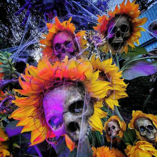 A group of skull-shaped sunflower ornaments arranged in a Halloween-themed outdoor display