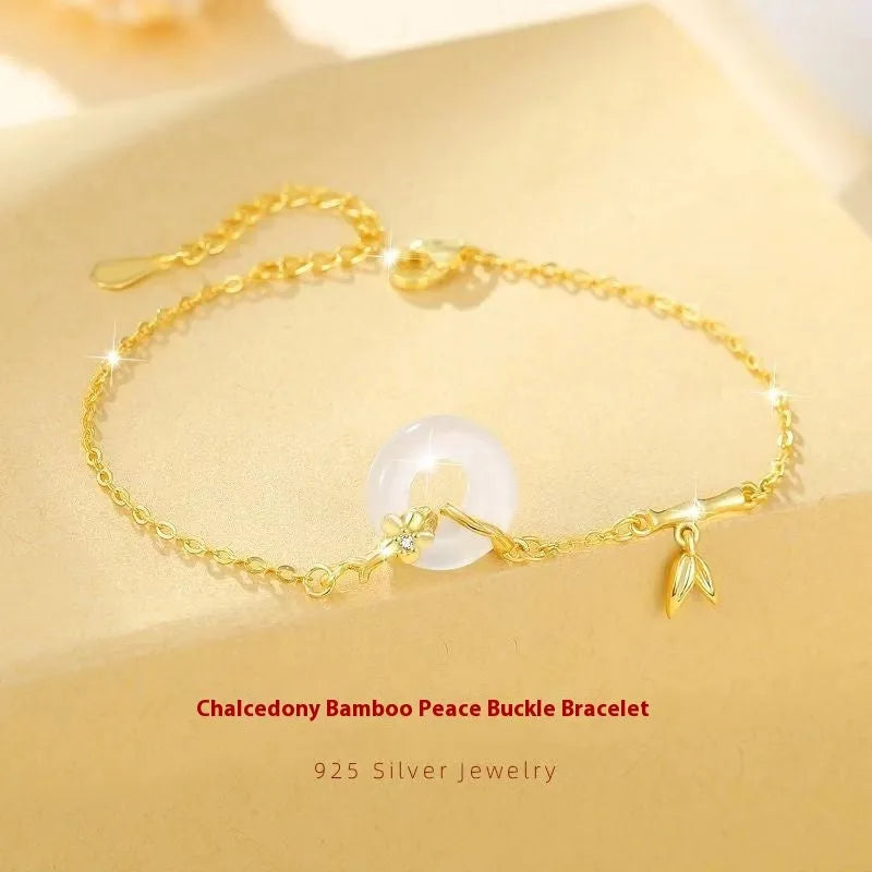 Gold-colour women's bracelet with peace symbol buckle and white chalcedony stone on silver band.