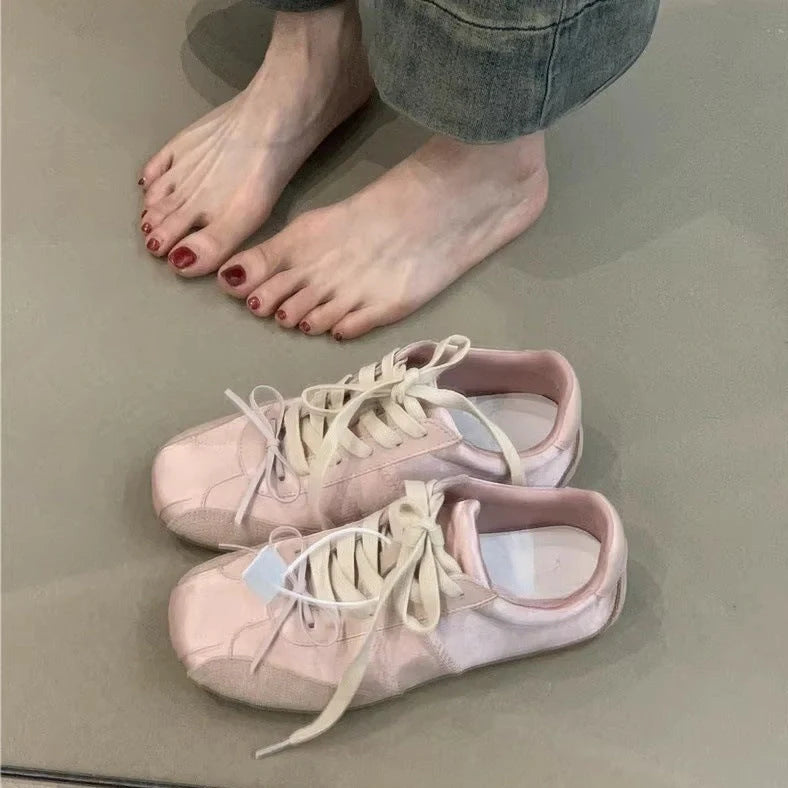 Women's low-top white sneakers with decorative bow detailing, available in black, pink, and beige colour options across UK sizes 35-40, featuring a round toe shape and durable rubber sole construction for everyday wear.