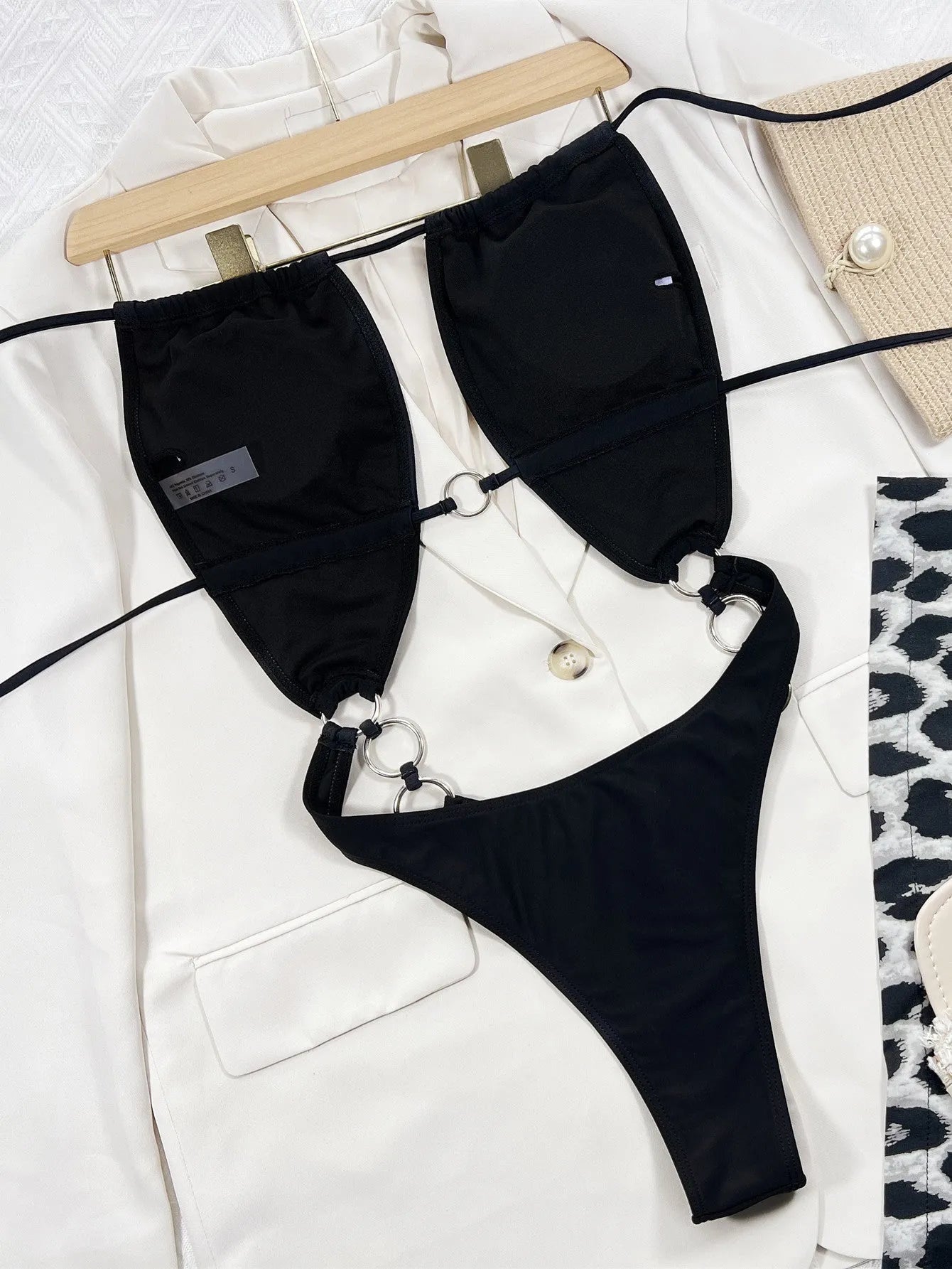 Black sleeveless one-piece swimsuit for women on a mannequin, showing steel ring detail and solid colour design.