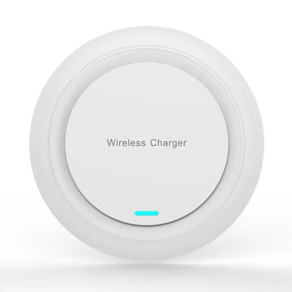Round white wireless charging pad on desk next to mobile phone