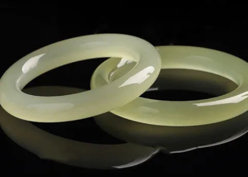 Ice-like silk jade bracelet with winding silk design and round bar beads on a wrist.