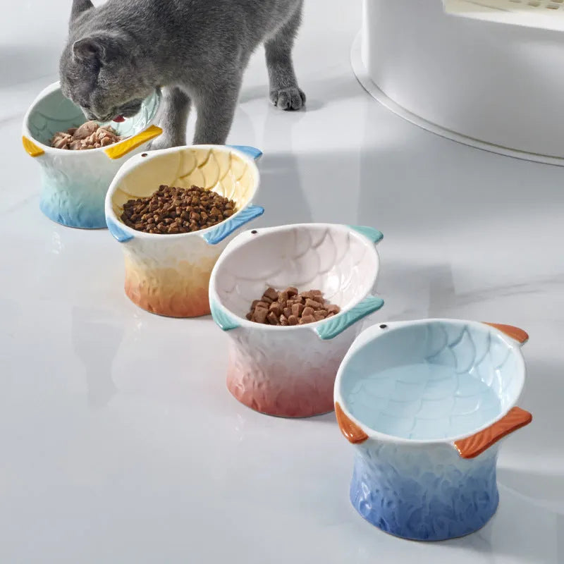 Set of four blue fish-shaped ceramic raised cat bowls on a wooden table