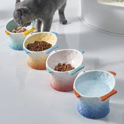 Set of four blue fish-shaped ceramic raised cat bowls on a wooden table