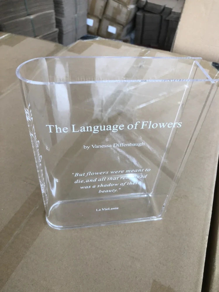 Transparent book-shaped acrylic vase, 22cm long with black font, refracting sunlight for home decor