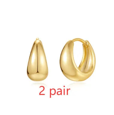 A pair of golden geometric clip-on earrings with a round design element on a white background.