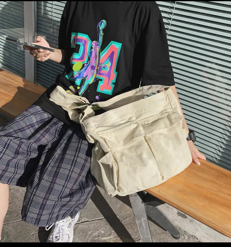 Canvas messenger bag in black, white, green, and brown with multiple pockets and adjustable strap