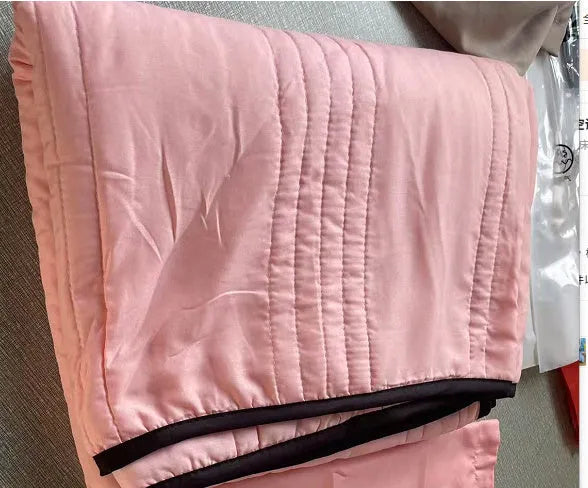 Lightweight plain coloured polyester summer quilt on a bed
