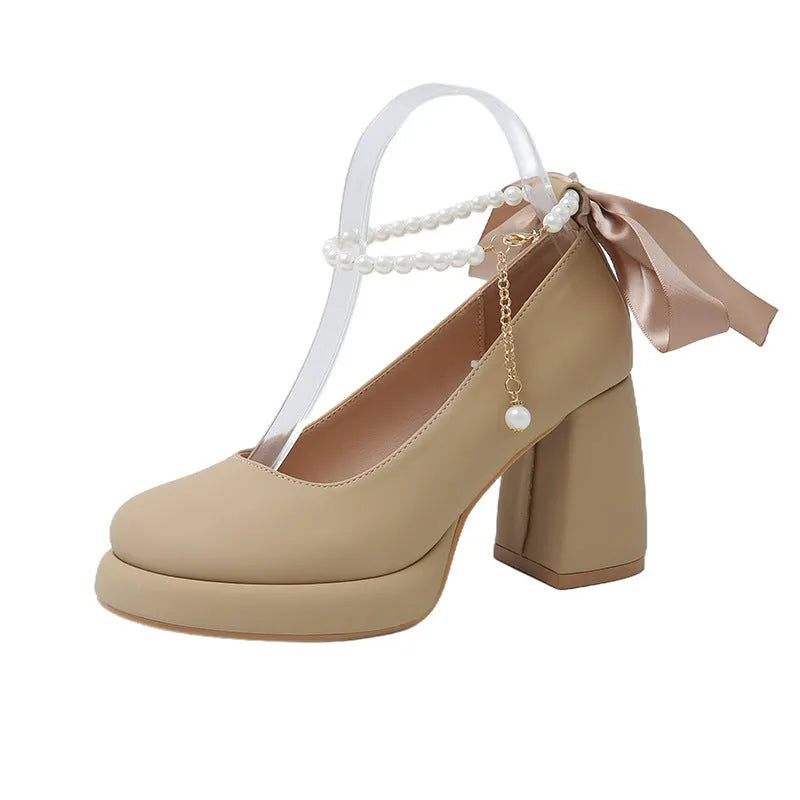 Women's beige Mary Jane shoes with chunky heel, ankle strap, pearl buckle, and round toe on a rubber sole.