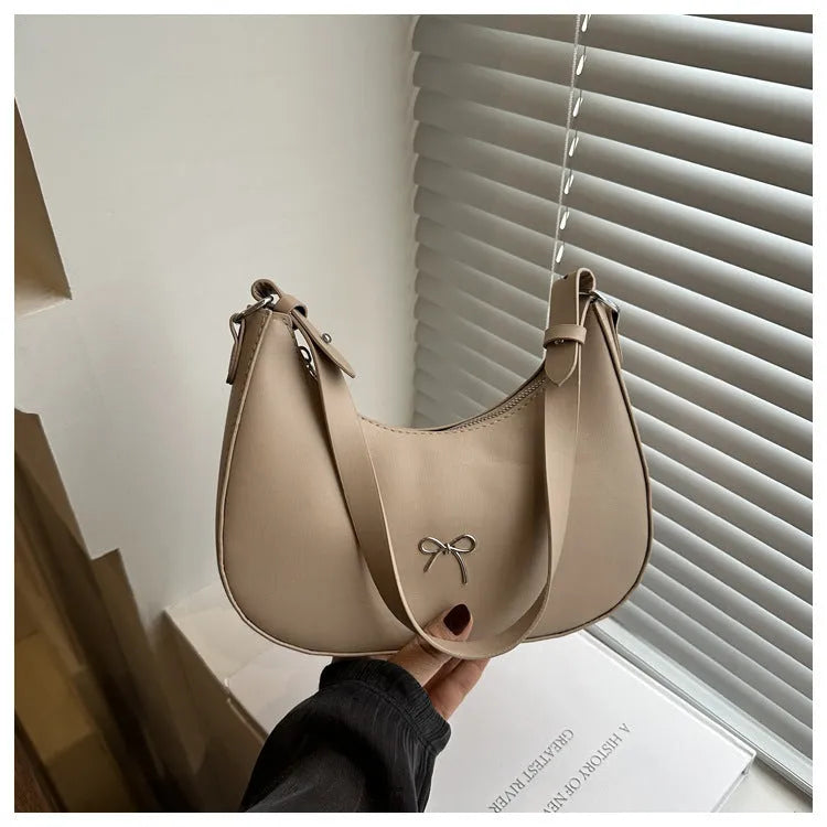 Women's silver dumpling-shaped PU crossbody bag showing front sandwich pocket and single shoulder strap.
