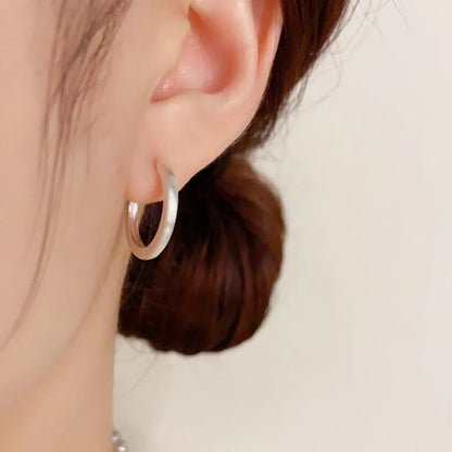 Geometric women's ear clip with round eyelet design in gold or silver colour