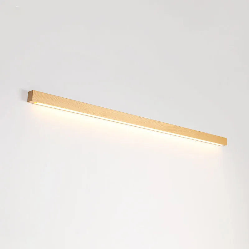A long, slim walnut-coloured wooden strip wall lamp with an integrated LED light source mounted on a plain wall.