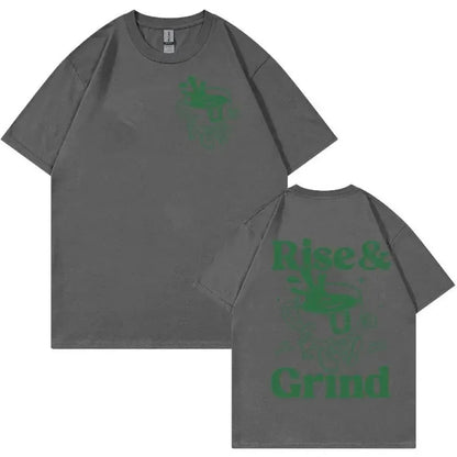 Man wearing a loose linen t-shirt with a printed Rise And Grind Green Coffee cartoon illustration.