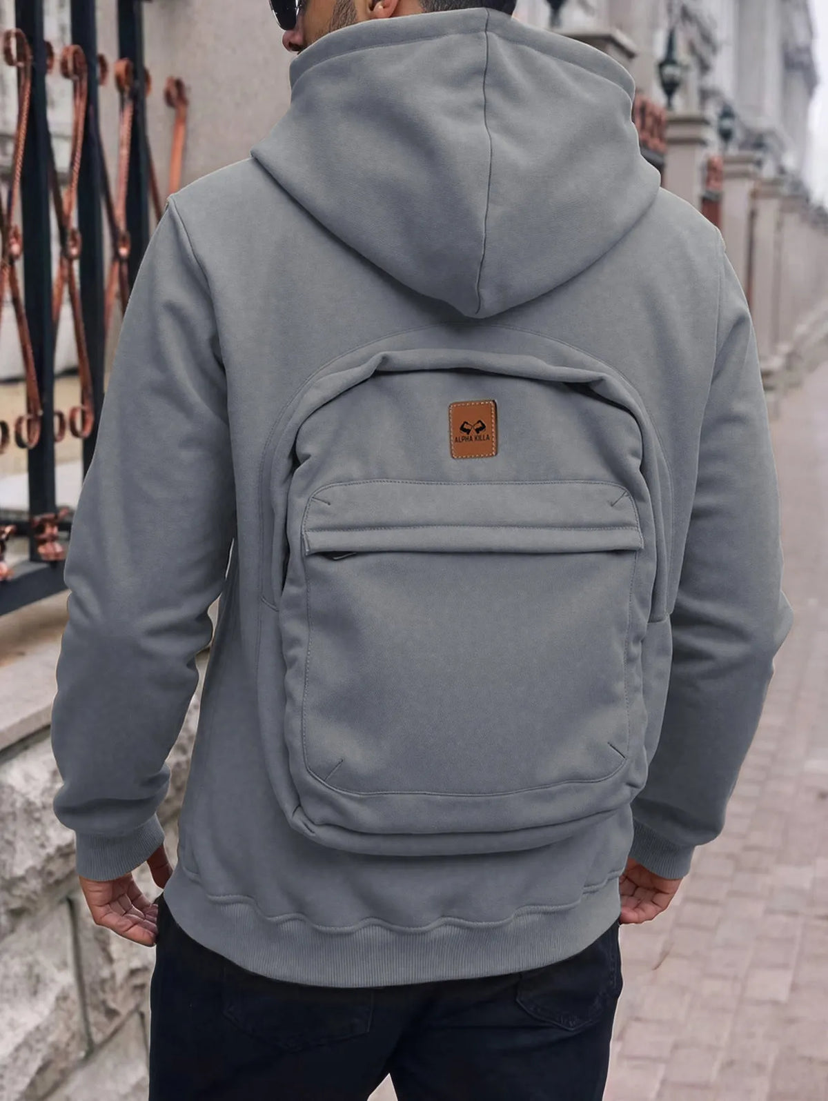 Men's loose-fit hoodie cardigan sweater with back schoolbag design and stick pocket in light grey, black and blue.