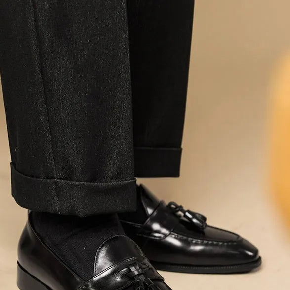 Men's black genuine leather tassel loafers with a rubber sole, shown from a side angle.