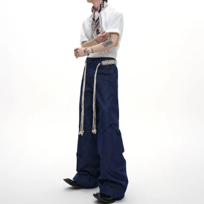 Men's dark blue straight-leg cotton jeans with 3D cutting, belt stitching, and decorative tassel on a hanger