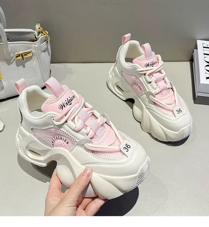 Women's pink sneakers with cross straps, thick sole, and mesh lining on a white background