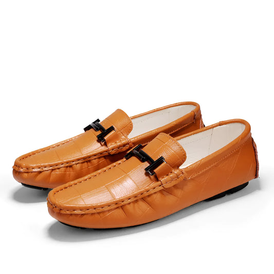Men's brown leather casual shoes with a belt buckle on the upper, shown on a wooden surface.
