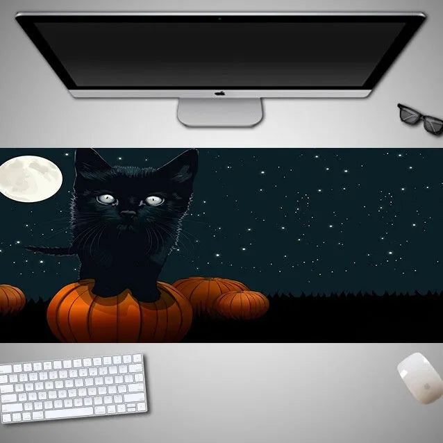 Oversized black Halloween-themed mouse pad with pumpkin design on a wooden desk, showing full 300mm width.