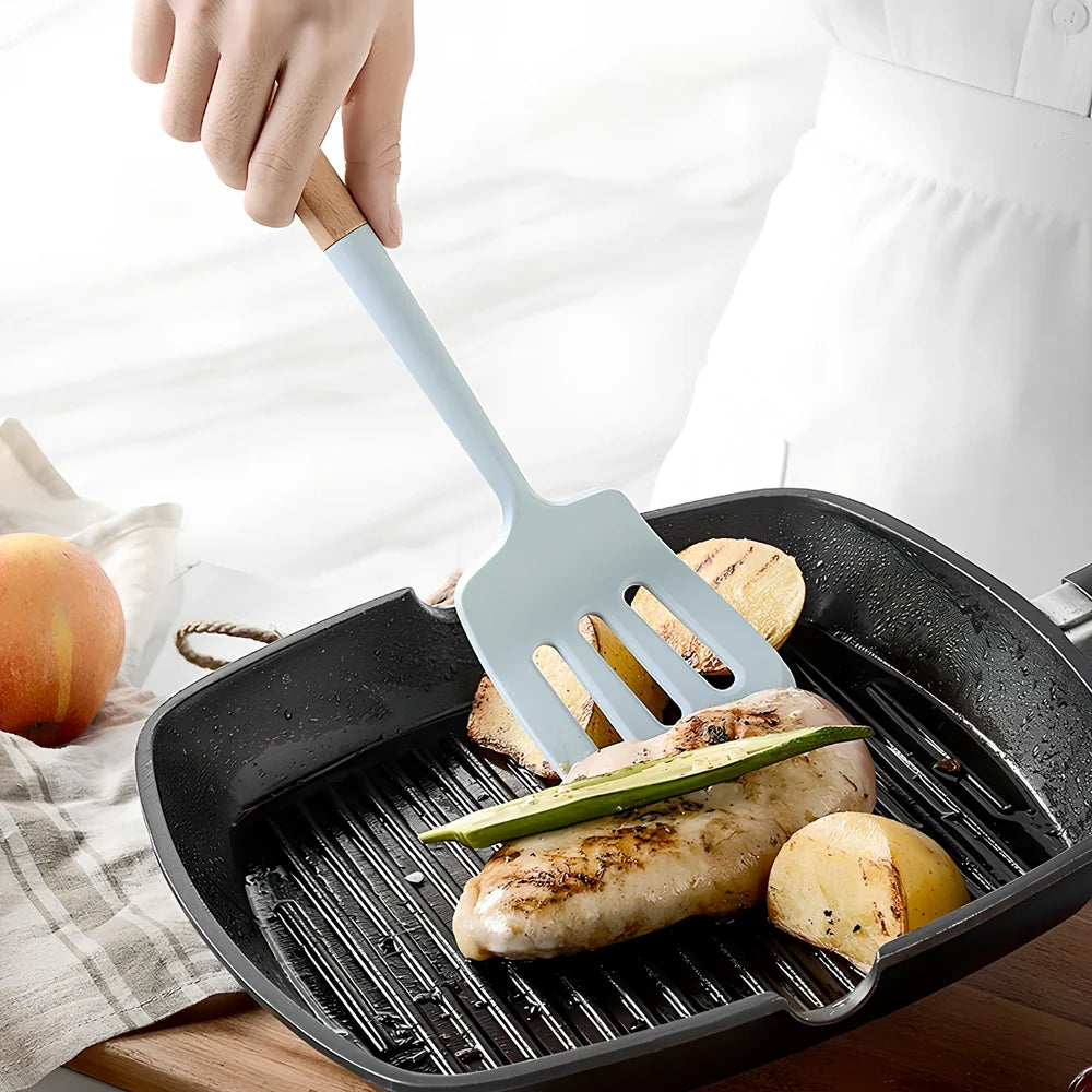 Blue silicone non-stick cookware set with frying spatula, colander, egg beater, and white iron storage bucket for kitchen organisation