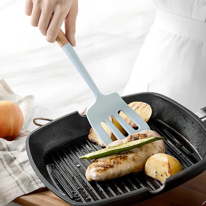 Blue silicone non-stick cookware set with frying spatula, colander, egg beater, and white iron storage bucket for kitchen organisation