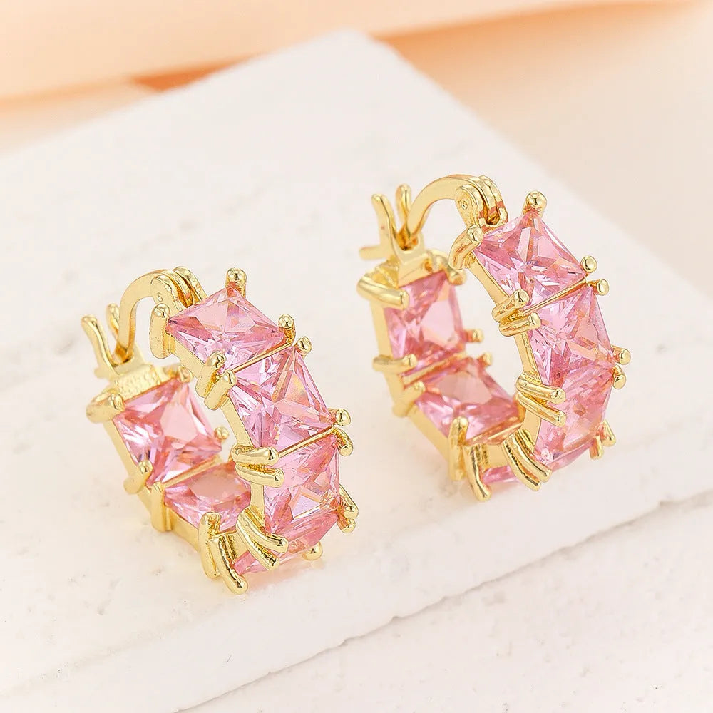 A pair of geometric U-shaped copper earrings with a round zircon stone in a gold-coloured setting.