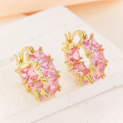 A pair of geometric U-shaped copper earrings with a round zircon stone in a gold-coloured setting.
