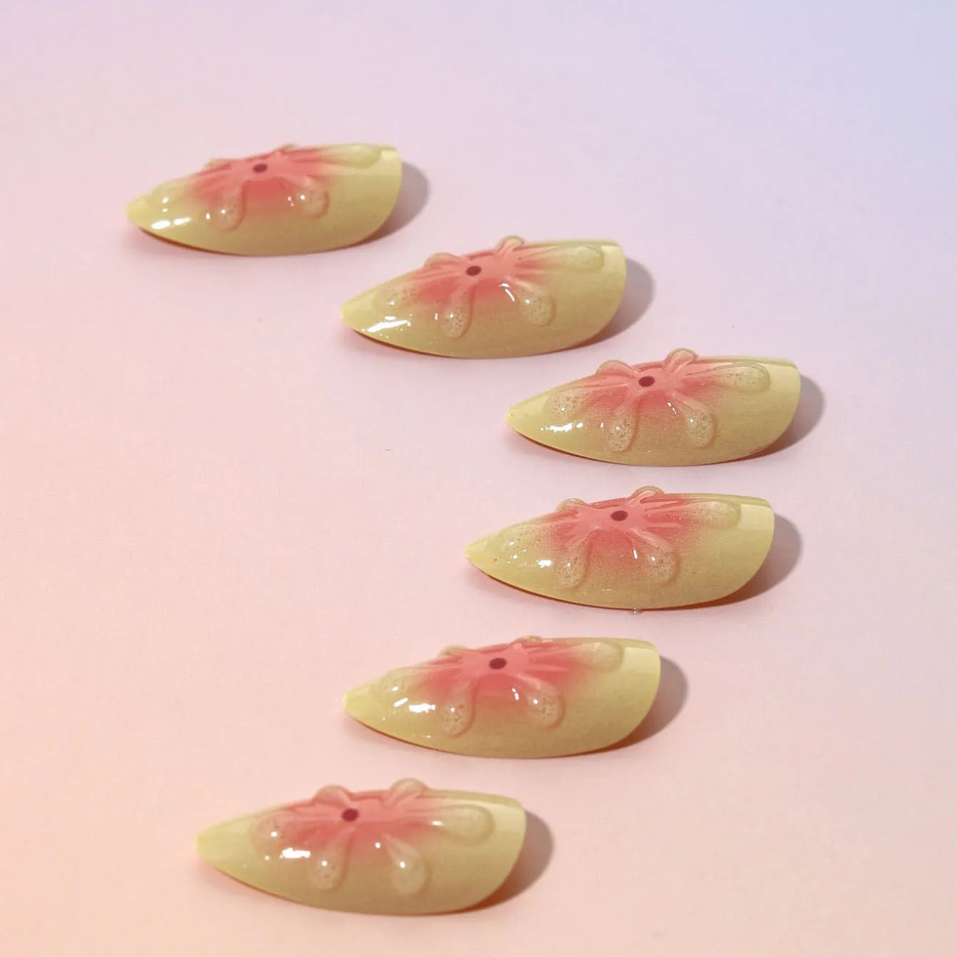 Set of plastic fake nails with pink and white 3D cartoon flowers, jelly glue, and a nail file.