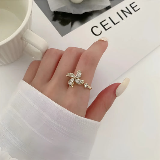 Gold-toned geometric ring with a central spinning windmill detail on a person's finger.