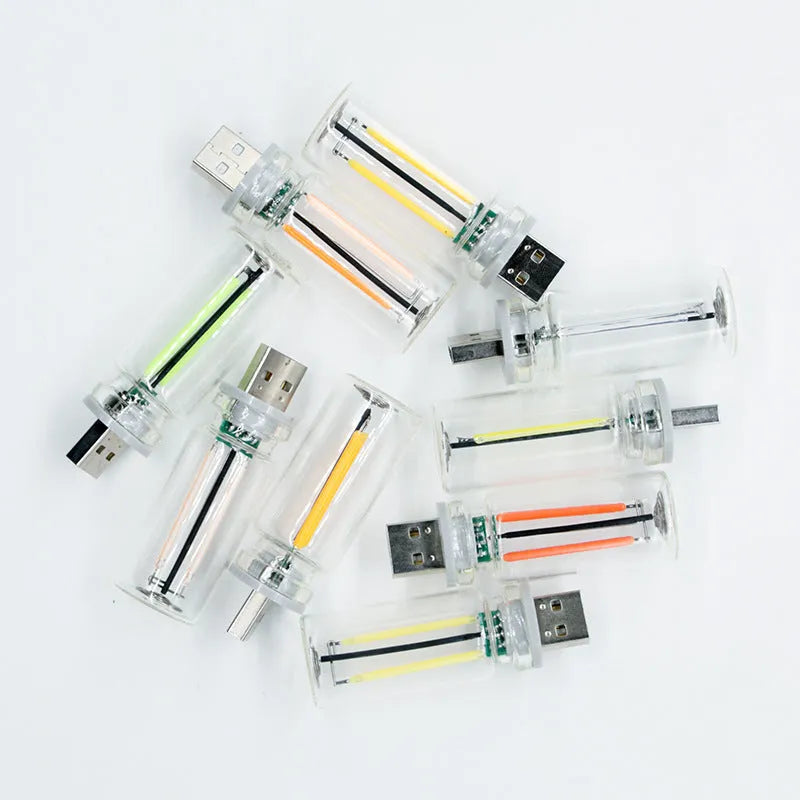 Small transparent glass USB touch night lamp with warm white light on a surface.