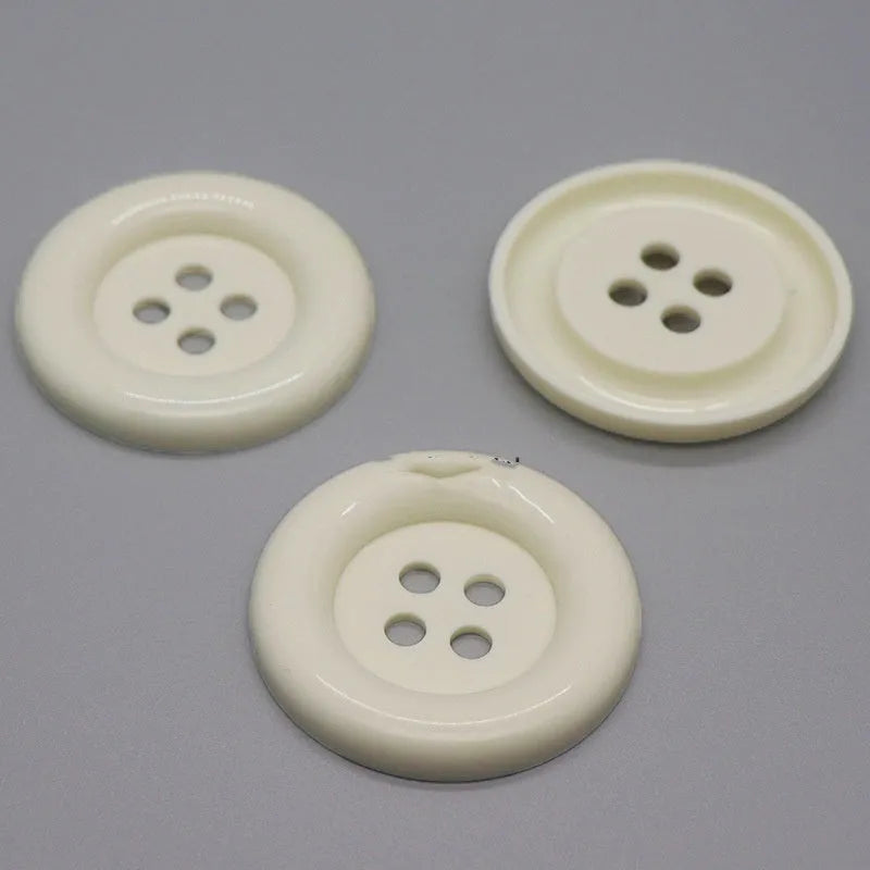 Assorted oversized round plastic buttons in various colours showing four-hole sew-through design.